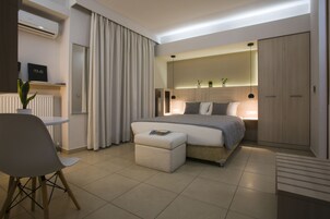 A modern bedroom with a bed, bedside table, chair, and a small table with a plant.