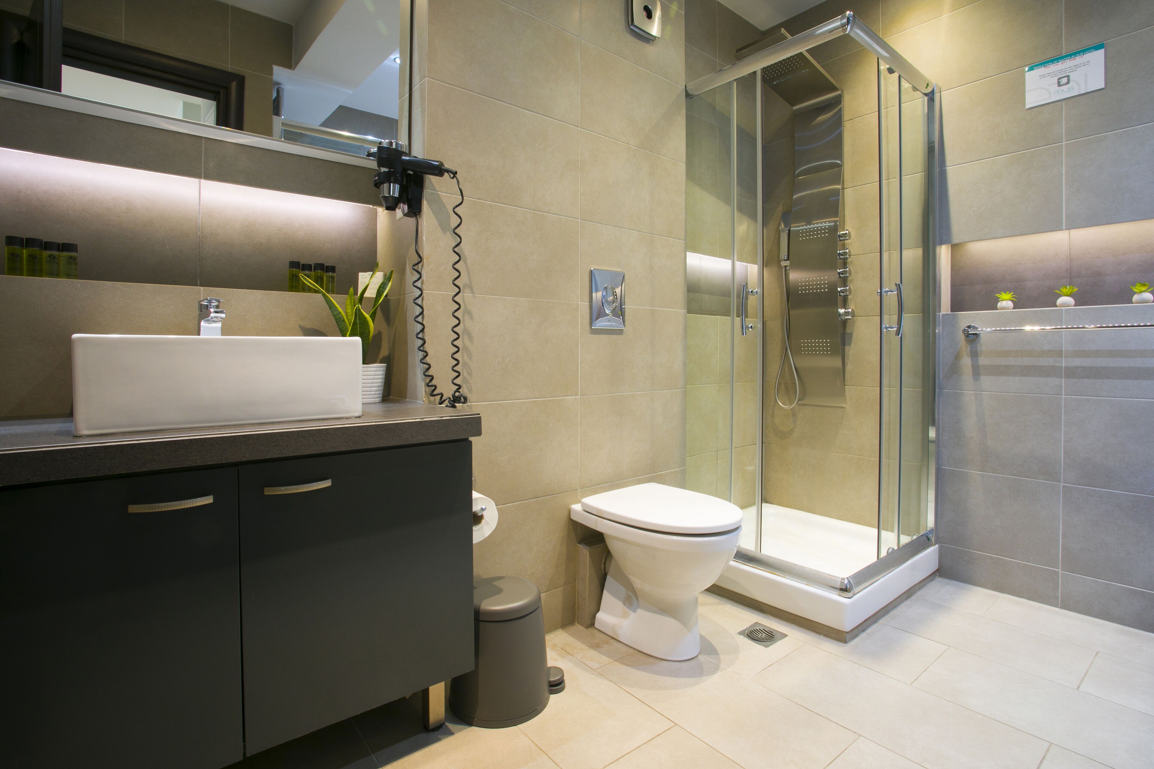 Un baño moderno con un lavamanos grande, inodoro y ducha a ras de suelo.