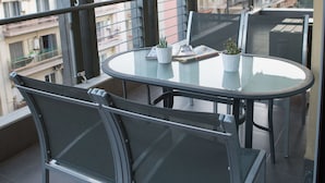 A balcony with a glass table, metal chairs, and a potted plant. - Polis Apartments (Thessaloniki)