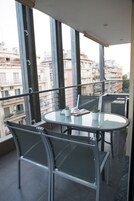 A balcony with a glass table, metal chairs, and a potted plant.