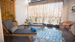 A sunlit room with two lounge chairs, a small table with a drink, and a wicker chair. - Polis Apartments (Thessaloniki)