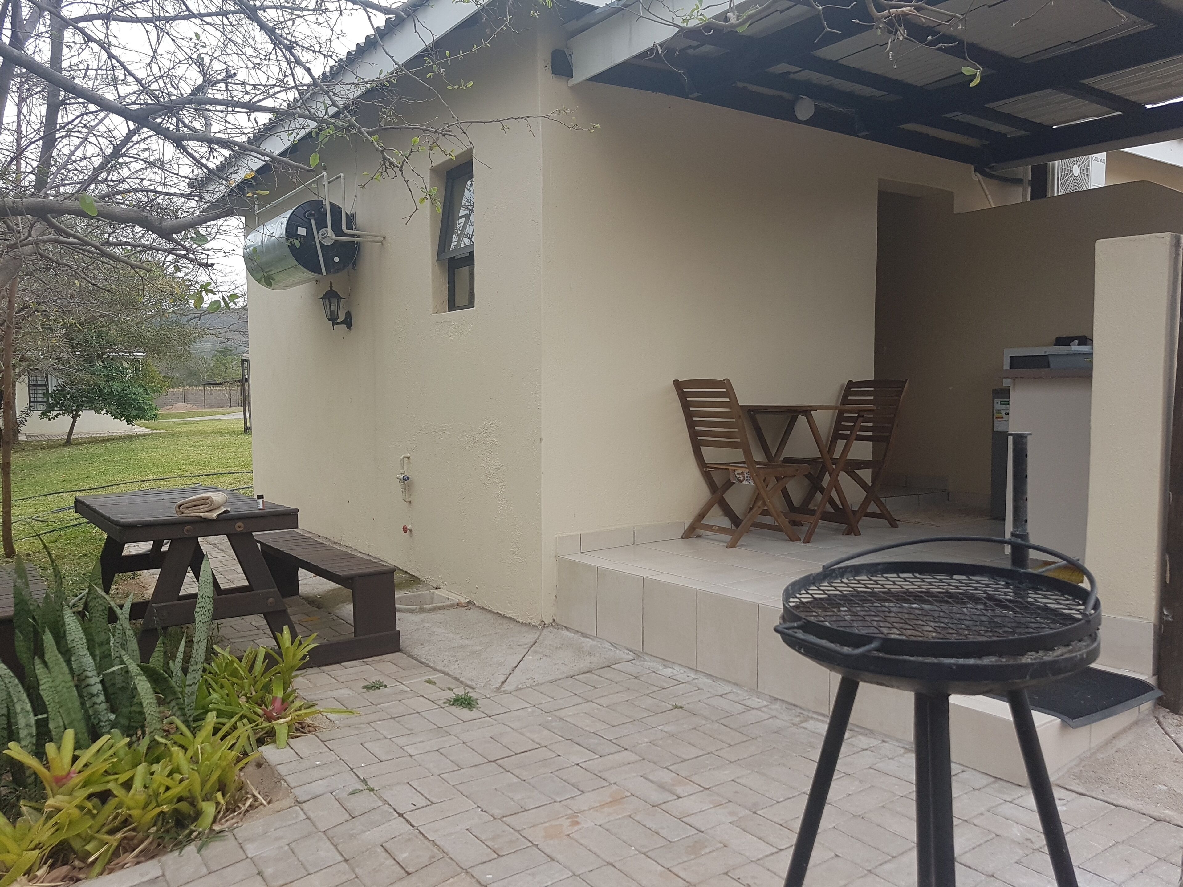 A patio with a table and chairs, a grill, and a small garden area.