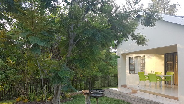 Une maison moderne dotée d’un patio, de chaises vertes et d’une table à manger.