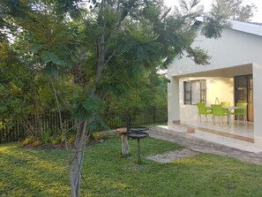 A modern house with a patio, green chairs, and a dining table. - Sand River Cottages (Mbombela)