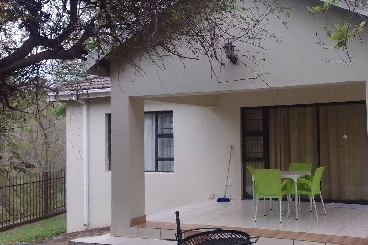 A building with a covered patio area, a table with chairs, and a window.