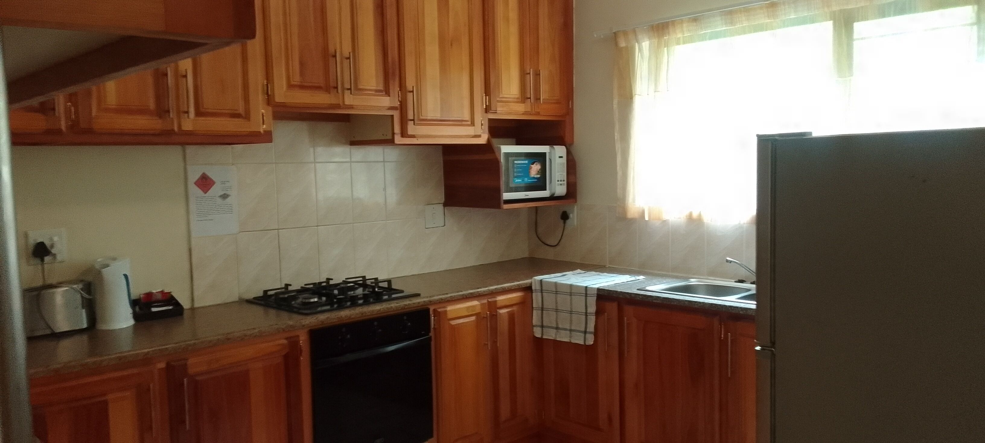 A kitchen with wooden cabinets, a microwave, a stove, and a dishwasher.