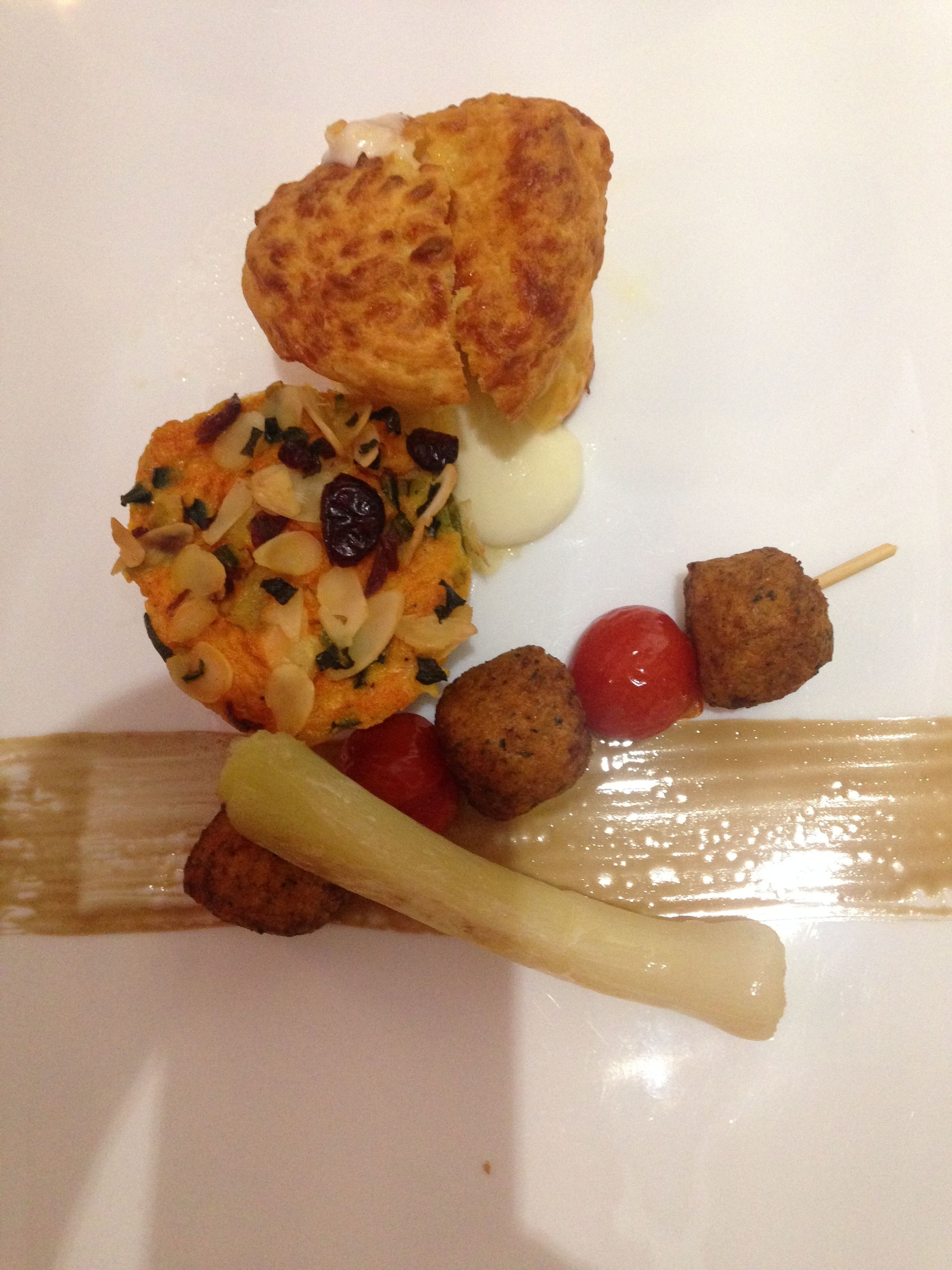 Une assiette contenant divers aliments, notamment un morceau de pain, un légume farci, des boulettes de viande et un bâtonnet de céleri.