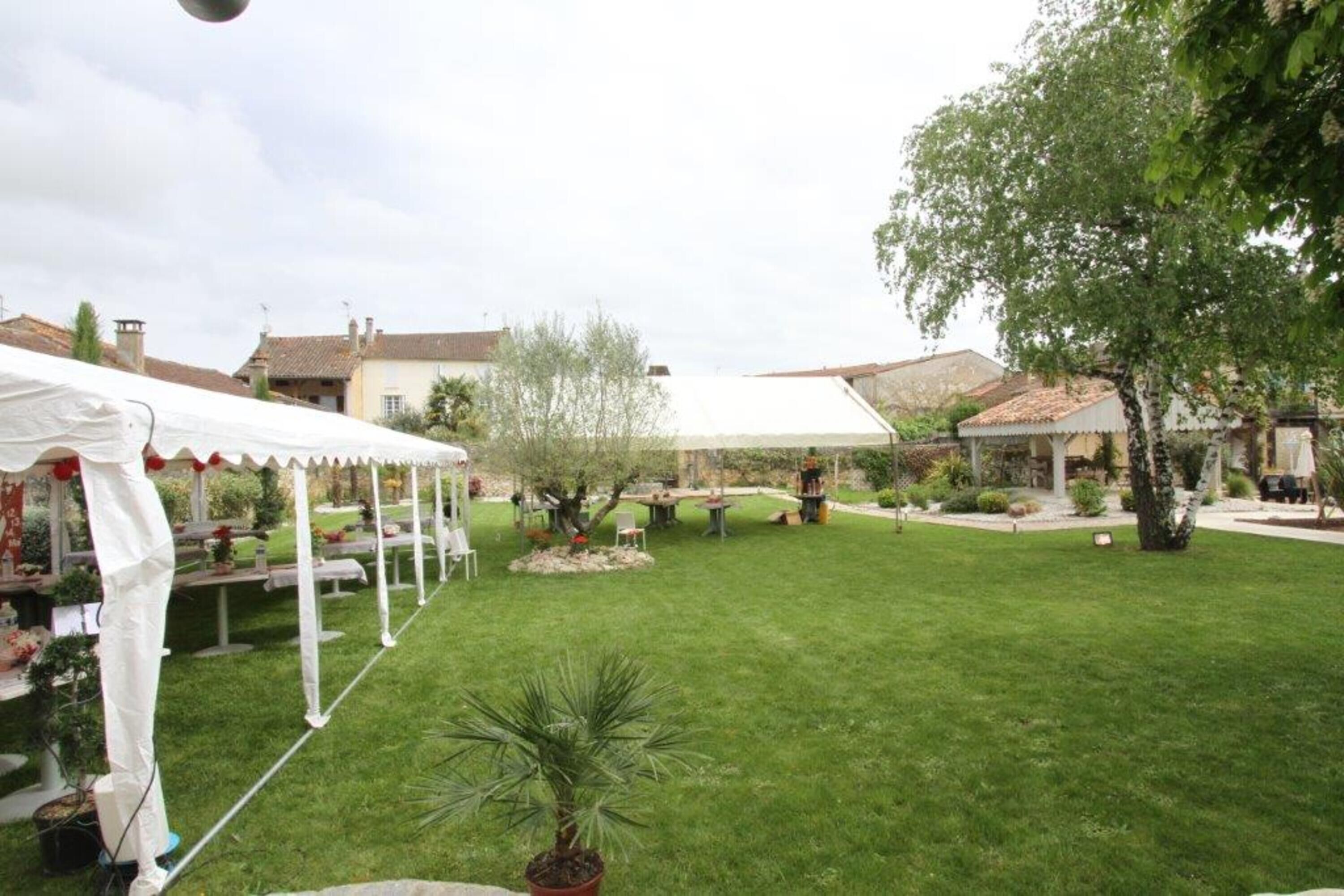 Un cortile con una tenda bianca, piante in vaso e mobili da esterno.