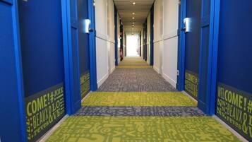 A hotel hallway with blue walls, a patterned carpet, and a sign welcoming guests.