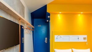 A hotel room with a bed, a door, and a wall-mounted light fixture. - Ibis Budget Perigueux Boulazac (Boulazac-Isle-Manoire)