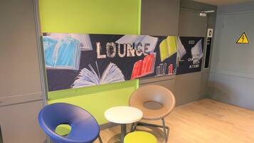 Ein Loungebereich mit einem Schild mit der Aufschrift 'LOUNGE' und einem kleinen Tisch mit Stühlen.