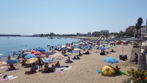 Een druk strand met talloze kleurrijke parasols en mensen die ontspannen op het zand.
