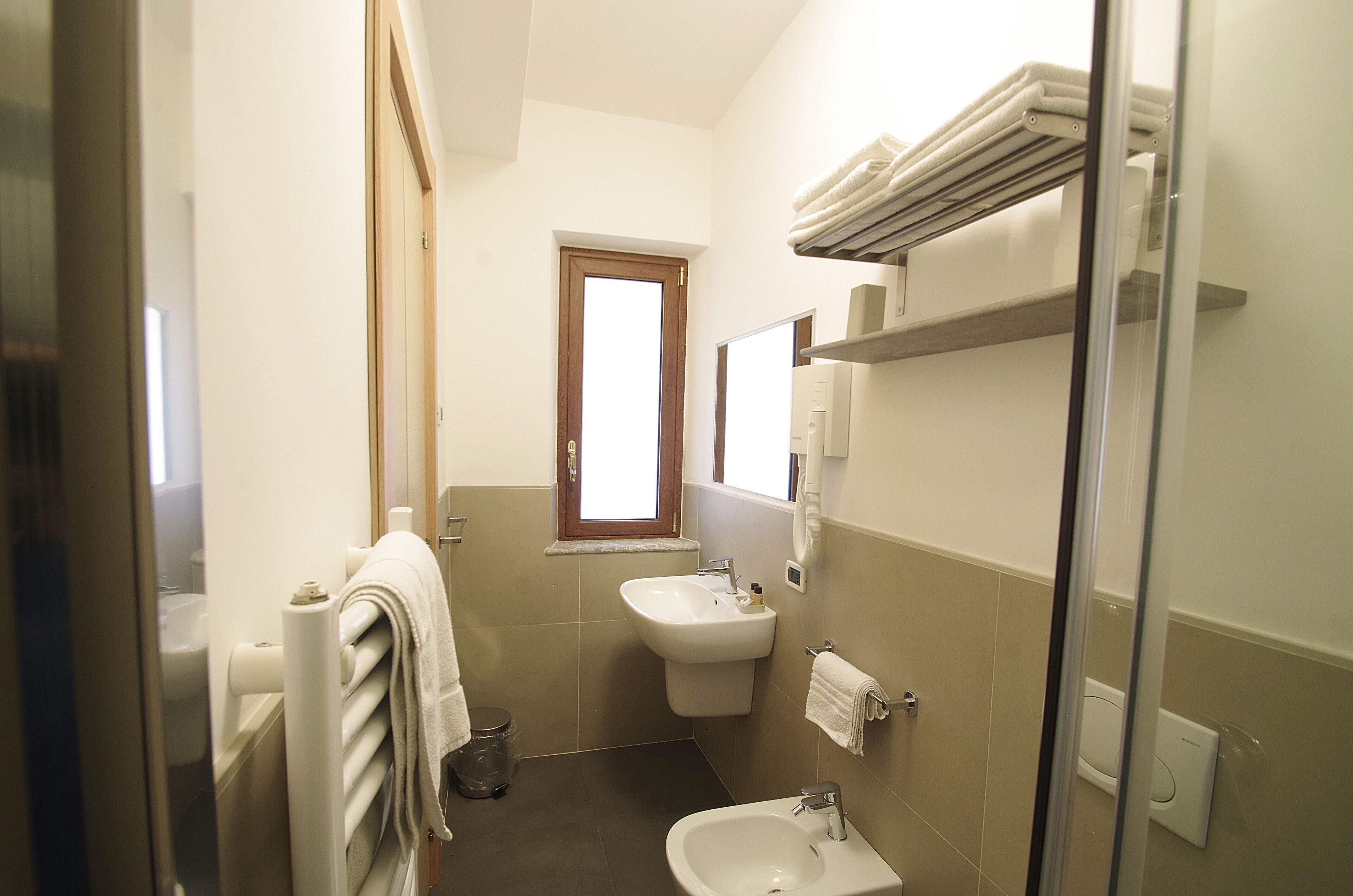 A compact bathroom with a sink, toilet, and a towel rack.