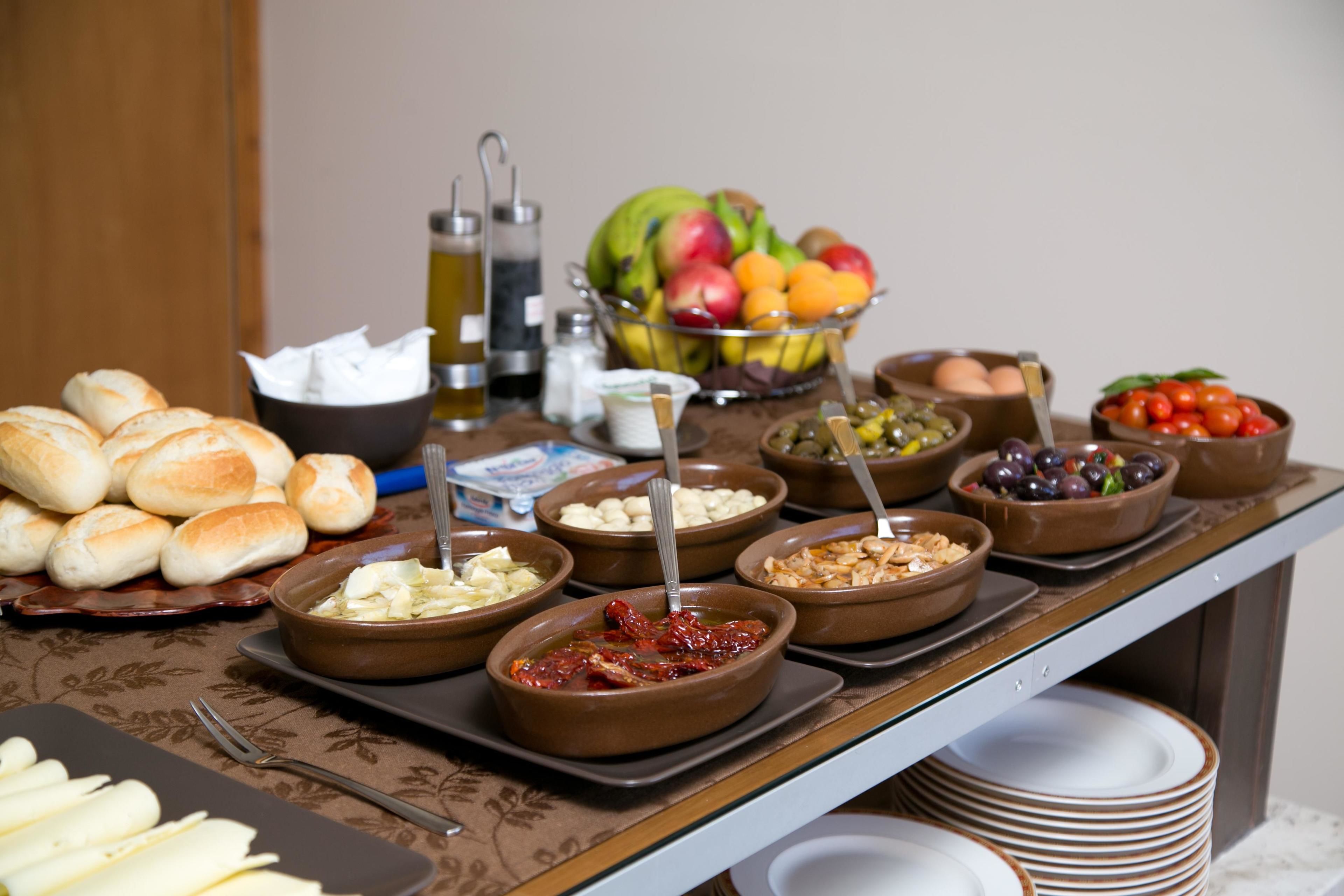 Une table de buffet proposant divers aliments, notamment du pain, des fruits et des sauces.