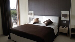 Een hotelkamer met een groot bed, twee nachtkastjes en uitzicht door een raam.