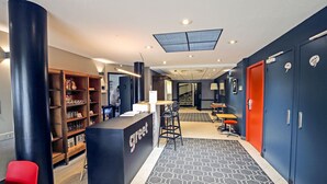 Een receptie met een balie, een boekenkast en een trap op de achtergrond.