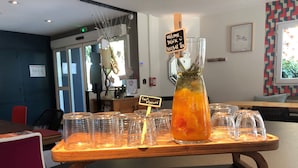 A bar area with a wooden bar counter, a large pitcher of herbal tea, and several glasses lined up on the counter.