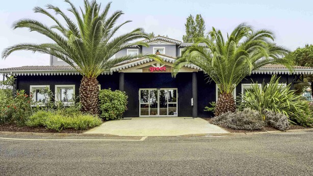 A building with a 'great' sign, palm trees, and a clear sky.