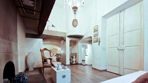 A spacious room with a large bed, a wooden chair, a white chest of drawers, and a chandelier. - Florentapartments - Santo Spirito (Florence)