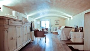 A spacious living room with a high ceiling, a large wooden cabinet, a brown armchair, a sofa, and a table with candles. - Florentapartments - Santo Spirito (Florence)