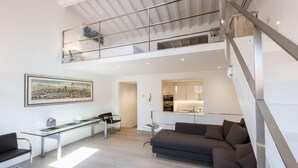 A spacious living area with a glass dining table, a sofa, and a staircase leading to an upper level. - Florentapartments - Santo Spirito (Florence)
