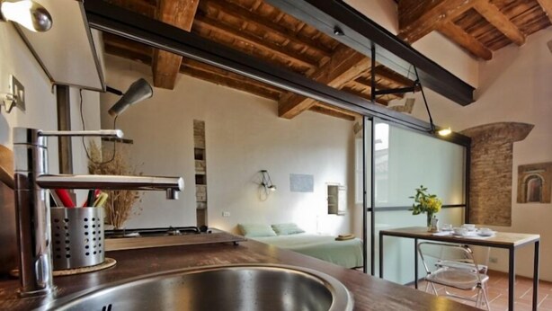 A modern kitchen with a large sink, wooden ceiling beams, and a view of a bedroom through an open door. - Florentapartments - Santo Spirito (Florence)