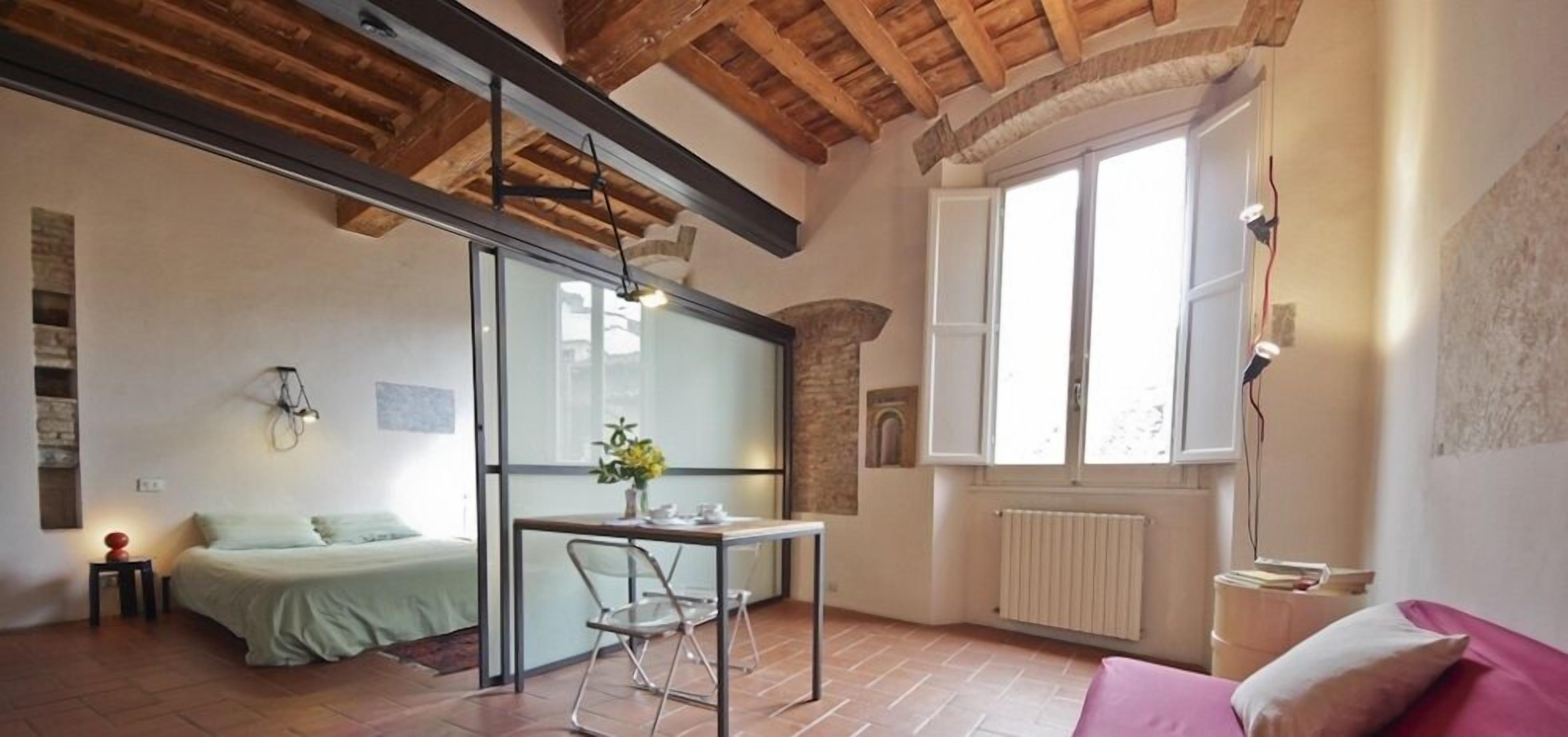 A room with a bed, a table with chairs, a window with a view, and a radiator.
