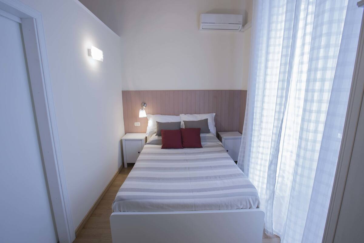 A neatly arranged bedroom with a bed, bedside tables, and a nightstand.