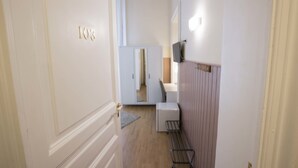 A narrow hallway with a door labeled '103', a small white cabinet, a mirror, and a radiator. - Dimora Novecento (Catania)