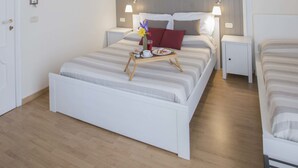 A hotel room with a large bed, two bedside tables, a nightstand, and a decorative ceiling. - Dimora Novecento (Catania)