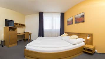 Una habitación de hotel con cama, escritorio, silla y televisor.