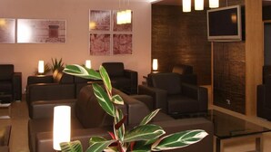 A modern lobby with seating areas, a television, and a large potted plant.