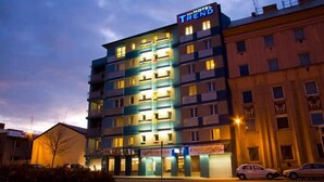 A multi-story hotel building with illuminated signage, balconies, and a ground-level entrance.