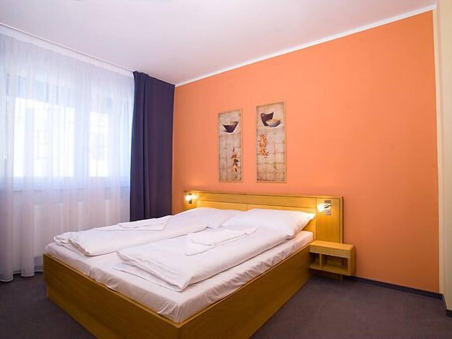 Ein Hotelzimmer mit einem Bett, einem Nachttisch und zwei an der Wand befestigten Kunstwerken.