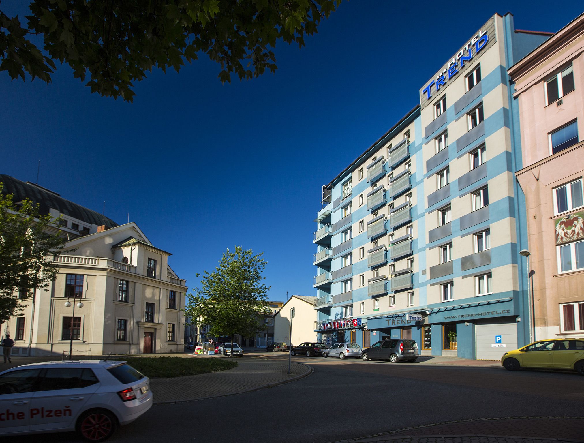 Um hotel com fachada moderna, várias varandas e o endereço do site visível.