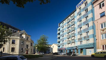 Um hotel com fachada moderna, várias varandas e o endereço do site visível.