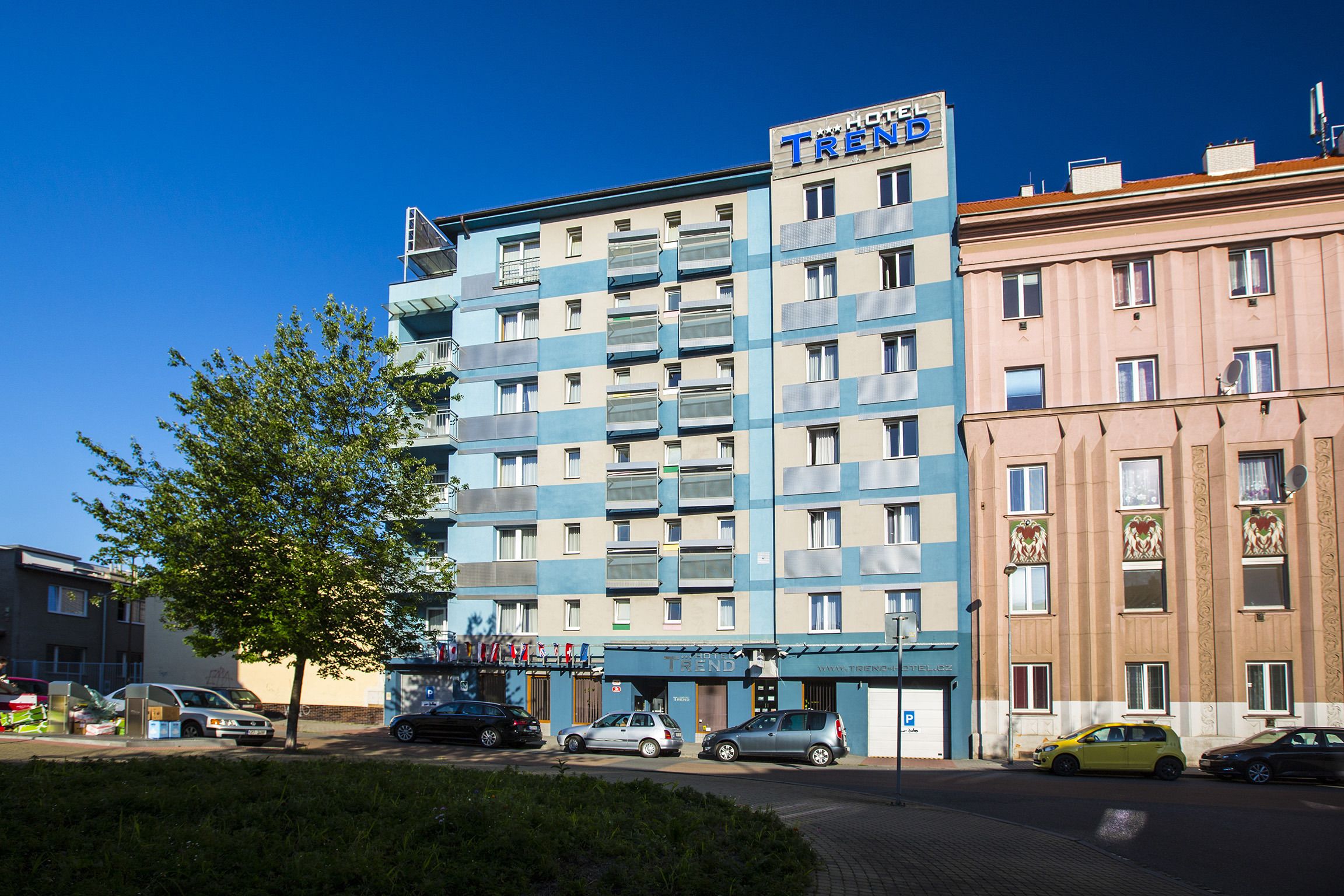 Un hotel de varios pisos con un llamativo letrero 'TRÉNB', balcones y un diseño moderno.