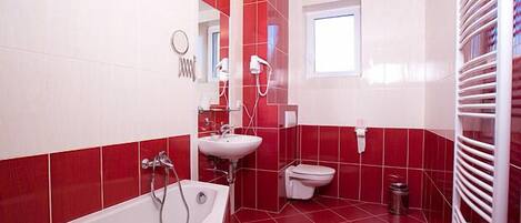 A bathroom with red and white tiles, a bathtub, a sink, a toilet, and a window.