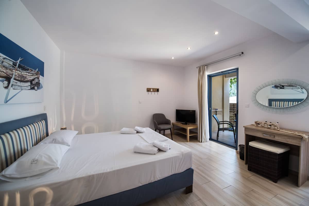 Habitación de hotel moderna con una cama grande, un escritorio, un televisor y un baño visible a través de una puerta abierta.