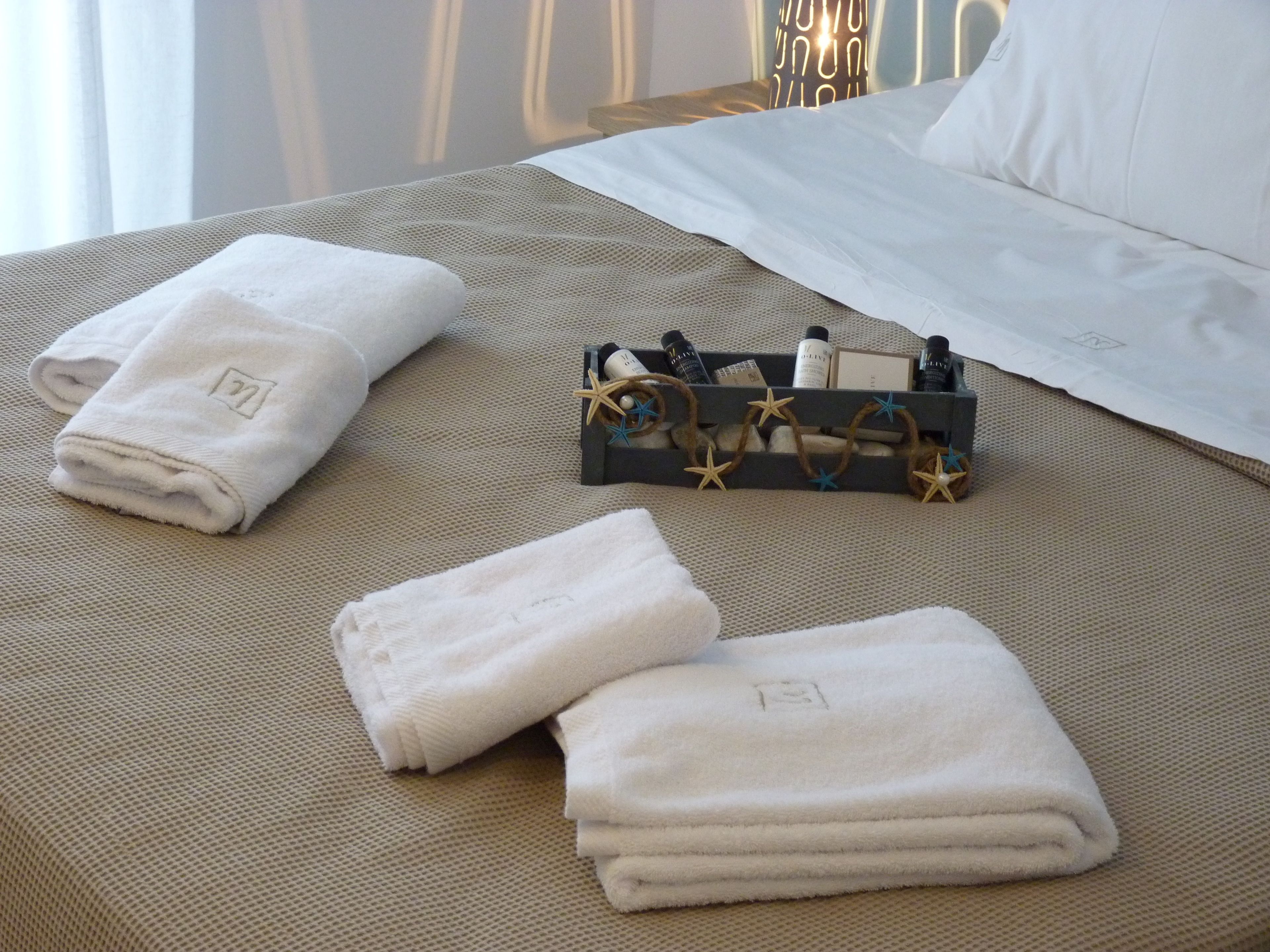 A neatly made bed with white linens, a small tray with toiletries, and a decorative star garland.