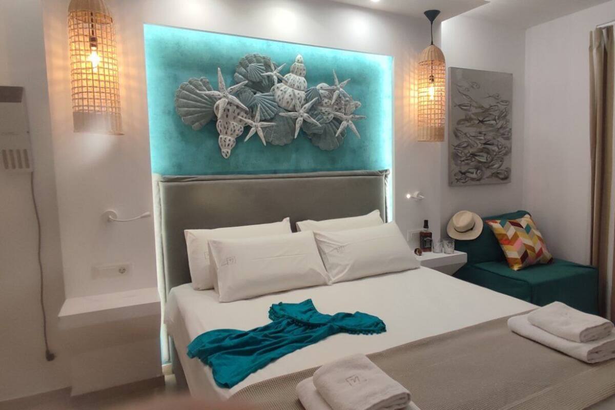 Una habitación de hotel moderna con una cama grande, una pared de acento color aguamarina y decoración mural.