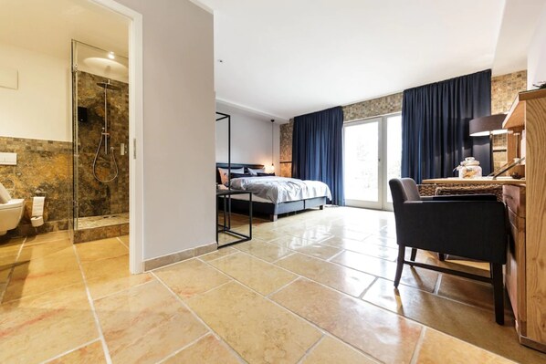 Una habitación de hotel moderna con ducha, cama, escritorio y una silla.