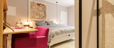 Un dormitorio con cama, escritorio, silla y un cuadro grande en la pared.