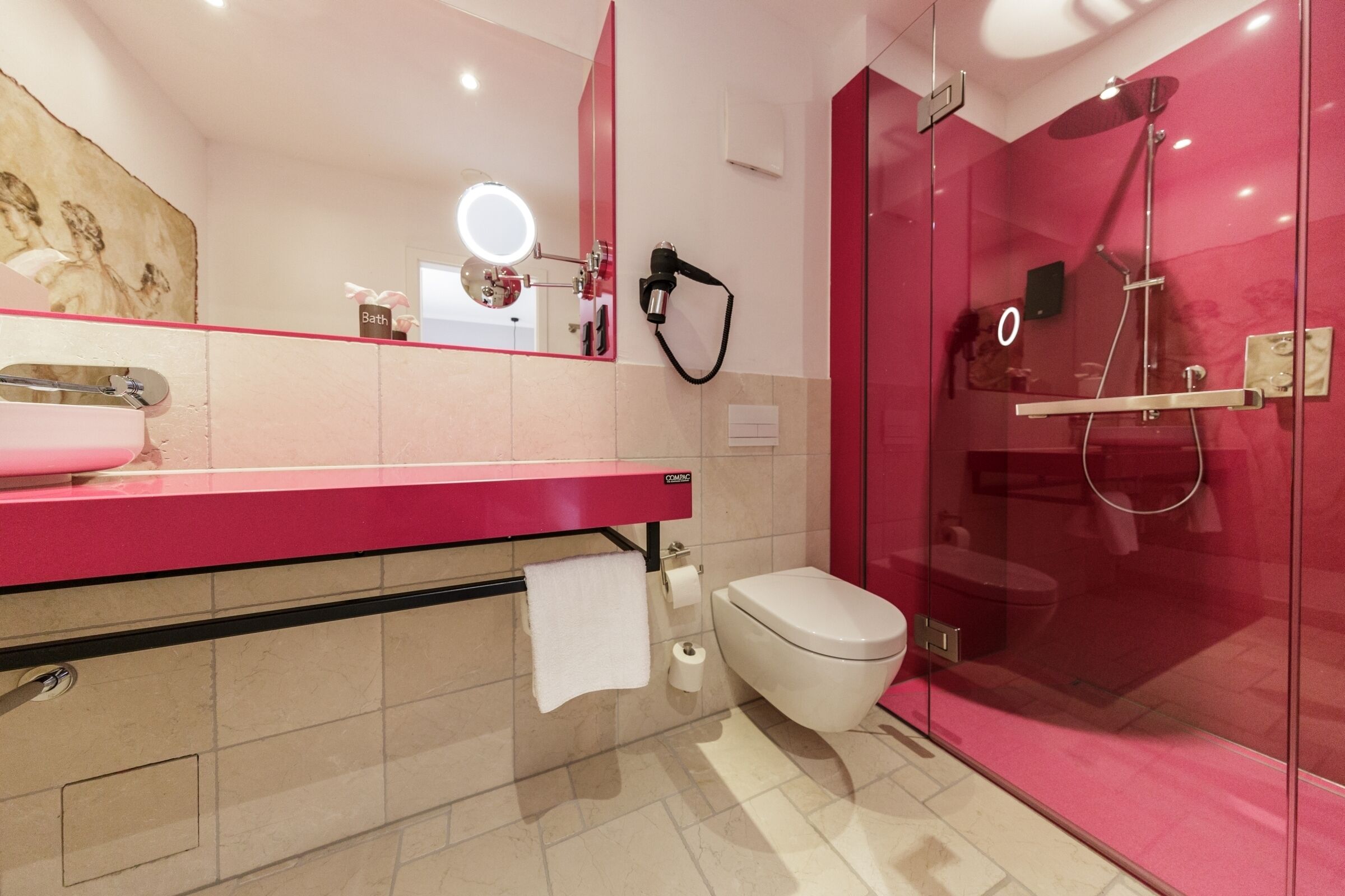 Un baño moderno con tocador rosa, cabina de ducha de vidrio y un inodoro.