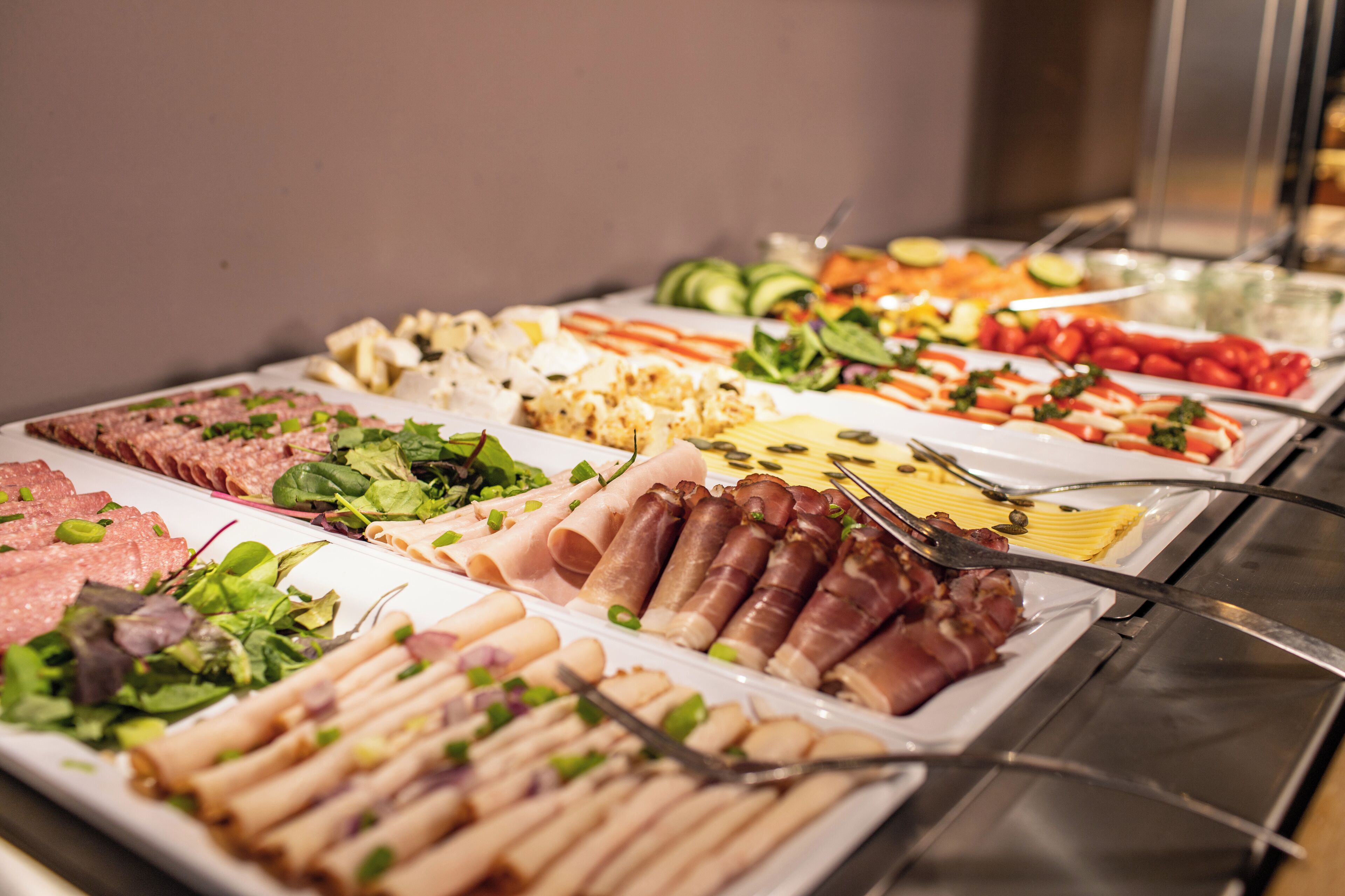 A buffet with various food items including meats, cheeses, and vegetables.