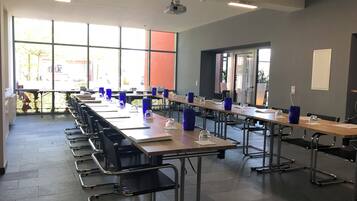A conference room with long tables, chairs, and blue glass candle holders.