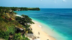 A beach with clear turquoise waters, a sandy shore, and lush greenery. - Adinda Balangan Beach Villa (Jimbaran)