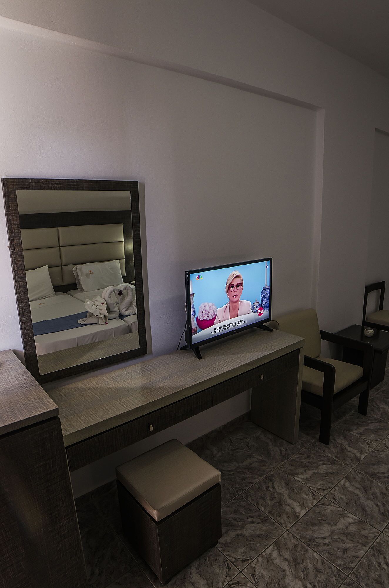 Una camera d'albergo con un grande specchio, una televisione, un letto e un angolo salotto.