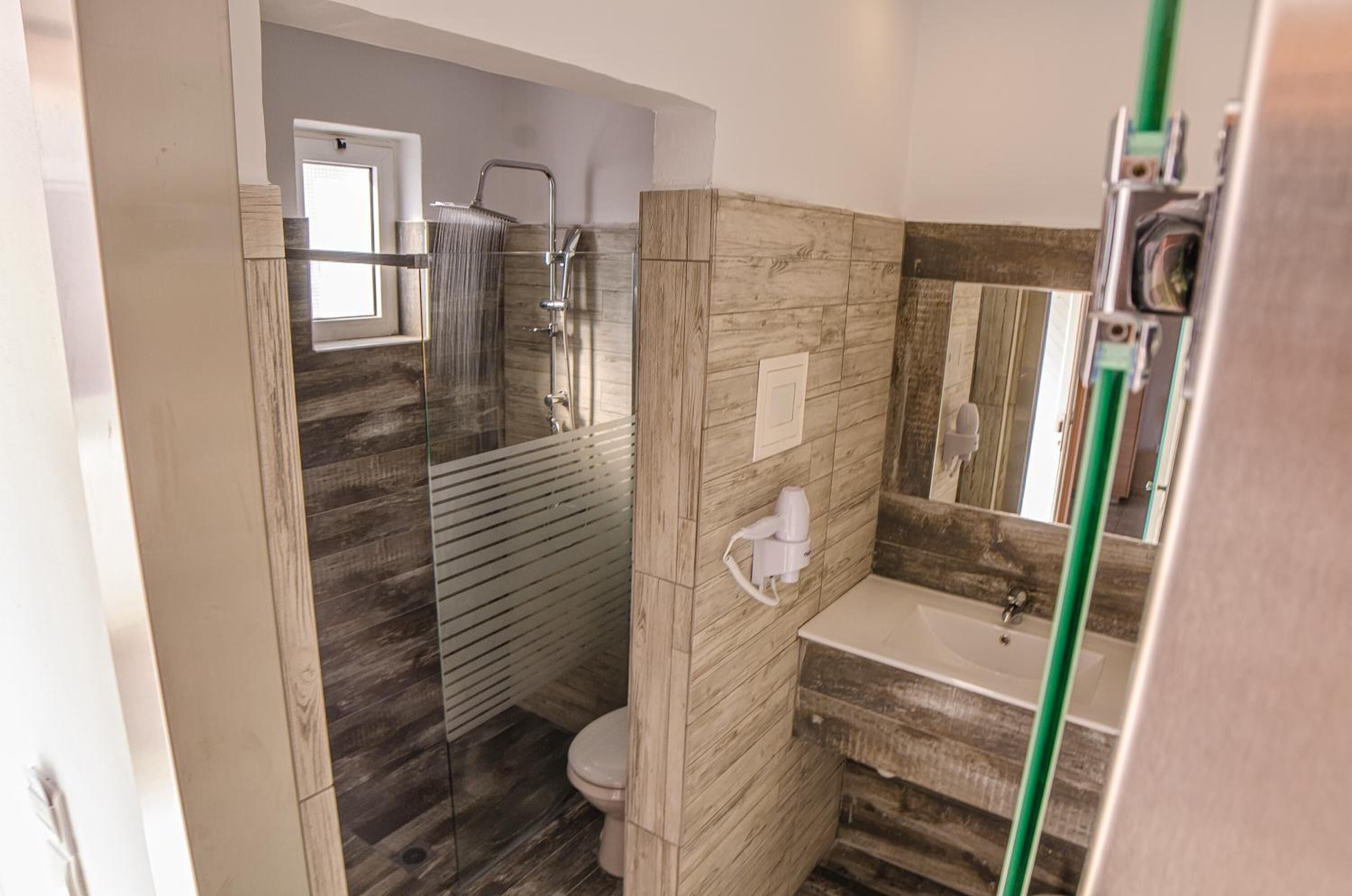 Een moderne badkamer met een douche met glazen wand, een toilet en een wastafel.