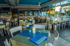 Un comedor interior con varias mesas y sillas, un centro de mesa con velas y un menú sobre la mesa.